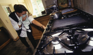 Woman checking for gas leak in cooker